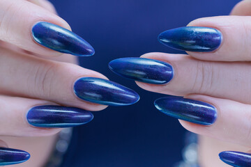 Woman's beautiful hand with long nails and dark blue manicure