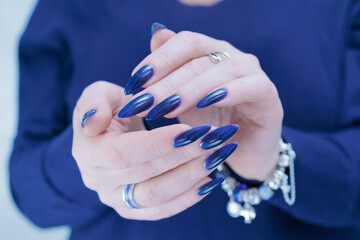 Woman's beautiful hand with long nails and dark blue manicure