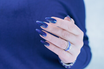 Woman's beautiful hand with long nails and dark blue manicure