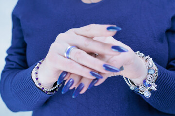 Woman's beautiful hand with long nails and dark blue manicure