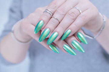 Female hand with long nails and light green and blue turquoise manicure 
