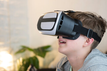 portrait of a happy 11 year old boy, child wearing virtual reality glasses at home, inside.