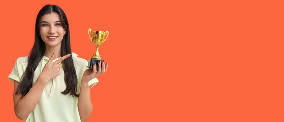 Sporty young woman with trophy cup on orange background with space for text