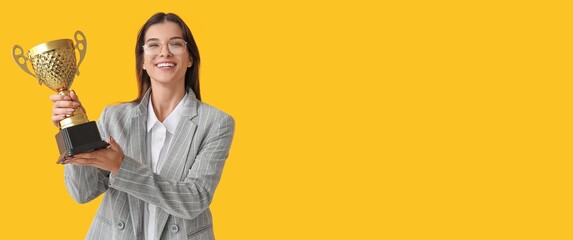 Happy young businesswoman with trophy cup on yellow background with space for text - Powered by Adobe
