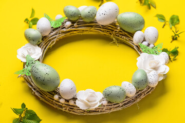 Easter wreath with flowers, eggs and butterflies on yellow background