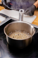 close-up of pot with a handle on the stove with alcohol and spices boiling