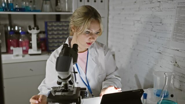 Focused woman scientist using microscope in a laboratory setting, surrounded by equipment