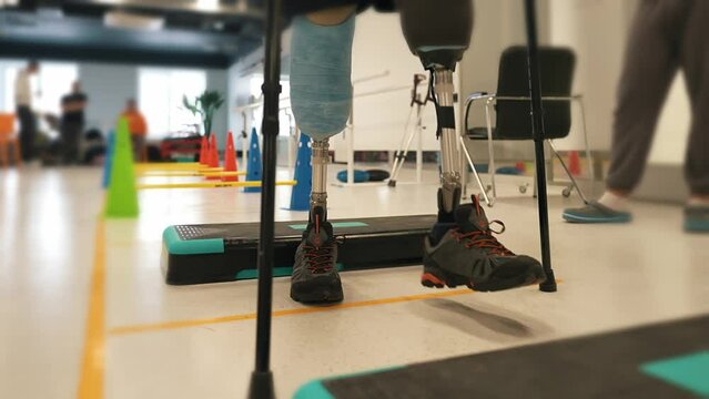 A disabled person with two prosthetic legs is undergoing rehabilitation. A disabled person with a disability. After being wounded and losing two legs, the soldier is rehabilitating with leg prostheses