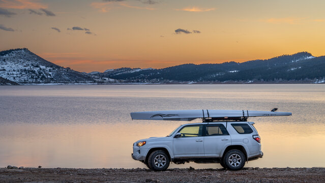 Loveland, CO, USA - February 13, 2024: Toyota 4Runner SUV with Liteboat rowing shell on roof racks on a shore of Carter Lake in northern Colorado at winter dusk.