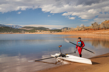 senior rower is rigging his rowing shell on a shore of Carter Lake in northern Colorado in winter scenery