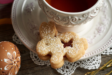 Homemade Linzer cookie in the shape of Easter bunny and a cup of tea