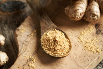 Ginger powder on a spoon with fresh root