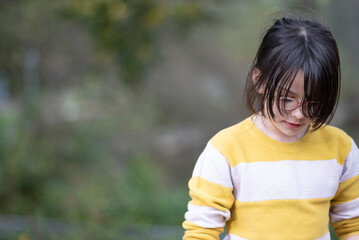 Asian little girl in yellow sweater and blue jeans in the park.