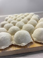 Dumplings made of dough and minced meat are stuck on the board
