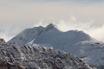 High winds lift snow into the air from off the peak of South Guardian Angle in Zion Nat. Park,...