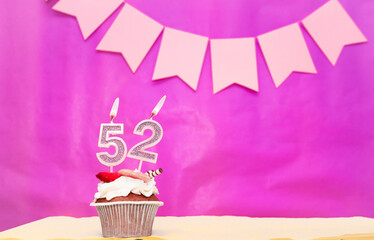 Background date of birth with number  52. Pink background with a cake and burning candles, save...