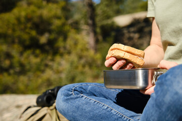 Woman seated taking out a sandwich out of a stainless steel lunch box.
