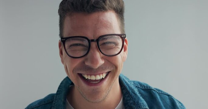 Man, face and glasses in studio with funny joke, laughing and happy with eyesight by grey background. Person, model and spectacles with comic smile, playful and excited for vision with eye care