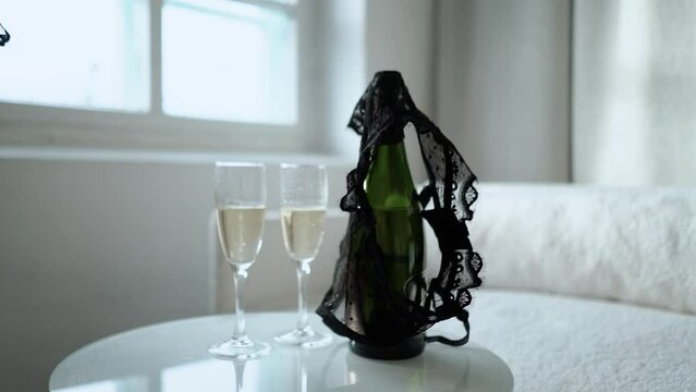 romantic date of a couple with two glasses of champagne, romance and love. The girl takes off and throws her black lace underwear, panties and bra on the table. Seduction and foreplay before sex