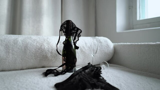 romantic couple date with champagne, romance and love. The girl takes off and throws her black lace underwear, panties and bra on the table. Seduction and foreplay before sex