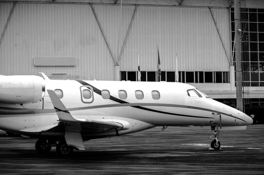 A black and white style photograph of a jet plane parked at a small airport