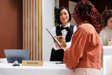Tourist checking in at luxury resort, writing registration files to keep records at reception...