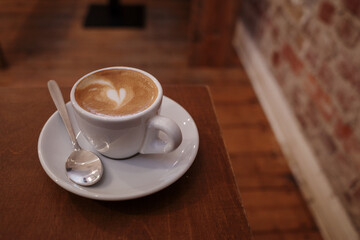 a freshly brewed latte with delicate heart-shaped art on top, served in a classic white ceramic cup...