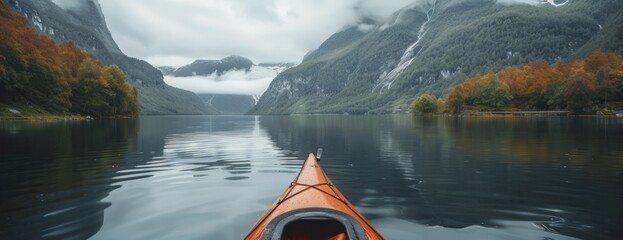 A kayak peacefully drifts on a calm lake, with majestic mountains serving as a breathtaking...
