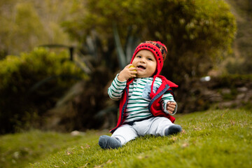 Un bebé sonriente con su chullo tejido, disfrutando del sabor de la naranja, pequeño tesoro...