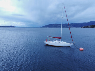 Fototapeta premium Sailboat in the sea in the evening sunlight over beautiful big mountains 