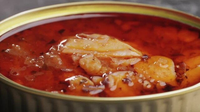 Opening canned octopus squid fish can, man open the canned seafood on the table. Close up on professional kitchen.