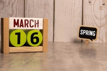 March 16 calendar date text on wooden blocks with blurred park background. Copy space and calendar...