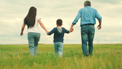 Dad mom child son run in nature. Mom dad, child play hand in hand outdoors. Happy family runs in...