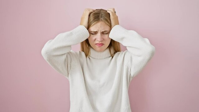 Stressed blonde beauty suffering agonising migraine, standing over pink isolated background, hand clutching head amid pain