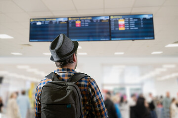 a tourist with a backpack looks at the airport departure board 