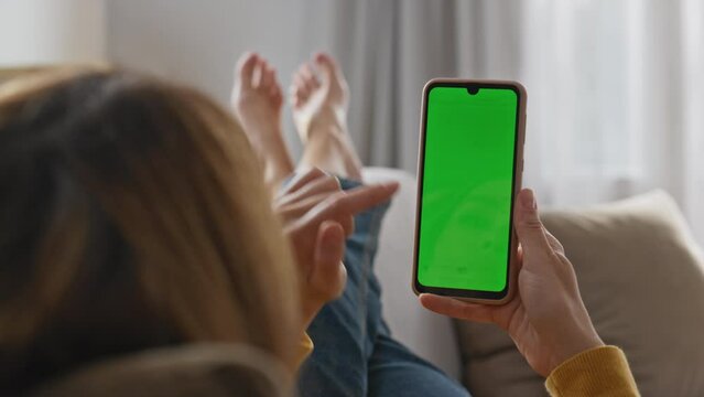 Lady scrolling greenscreen mobile phone at sofa closeup. Woman surfing web cell