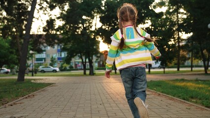 little girl running through park sunset, happy family, running foot along road kid girl daughter,...