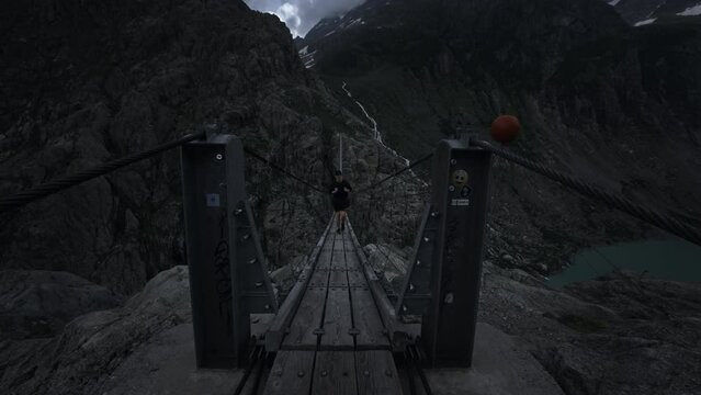 Male hiker walking on Triftbr&uuml;cke suspensions bridge in Innertkirchen Switzerland
