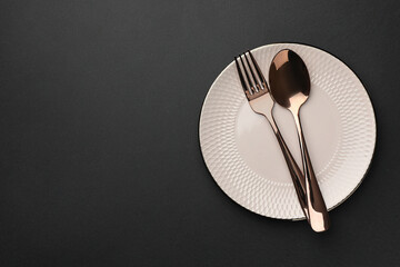 Clean plate and cutlery on black table, top view. Space for text