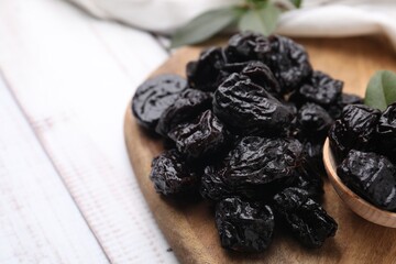 Tasty dried prunes on light wooden table, closeup. Space for text