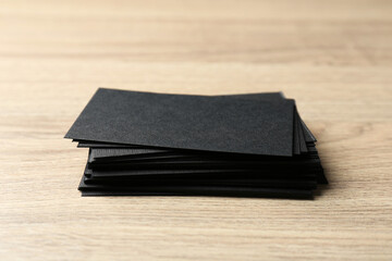 Blank black business cards on wooden table, closeup. Mockup for design