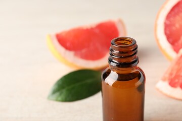 Grapefruit essential oil in bottle and fruit on table, closeup. Space for text