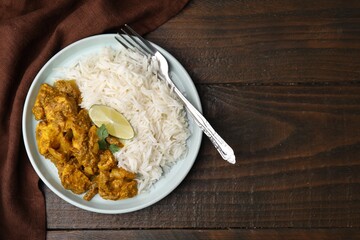 Delicious chicken curry with rice on wooden table, top view. Space for text