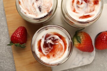 Tasty yoghurt with jam and strawberries on grey table, top view