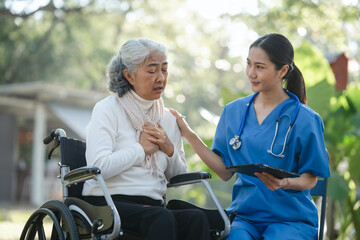 Fototapeta premium Compassionate Asian woman provides care to elderly person in wheelchair outdoors. Engaging in physical therapy, happiness, encouraging positive environment for mature individuals with grey hair.