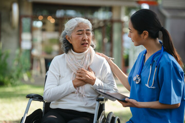 Fototapeta na wymiar Compassionate Asian woman provides care to elderly person in wheelchair outdoors. Engaging in physical therapy, happiness, encouraging positive environment for mature individuals with grey hair.