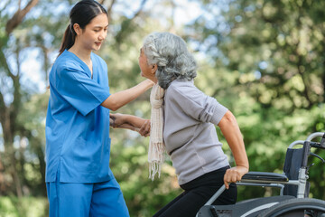 Compassionate Asian woman provides care to  elderly person in wheelchair outdoors. Engaging in physical therapy, happiness, encouraging positive environment for mature individuals with grey hair.