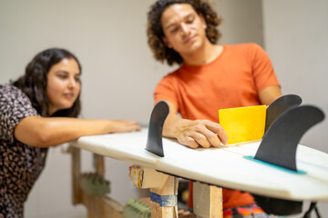 Workers checking the symmetry level of a surfboard in workshop