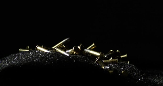 Close up shot of loose gunpowder pile with .22 Long Rifle bullets falling on