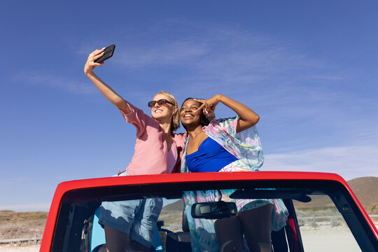 Young African American woman and young Caucasian woman take a selfie outdoors on a road trip